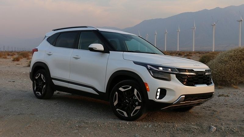 2024 Kia Seltos SX in white near Palm Springs wind turbines at sunset