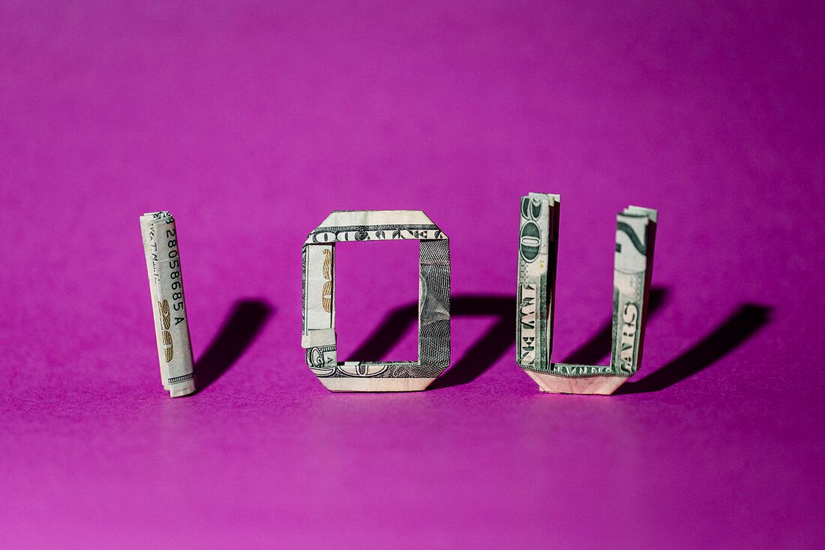 The letters "IOU" are spelled out using folded U.S. dollar bills to demonstrate the concept of lending money.